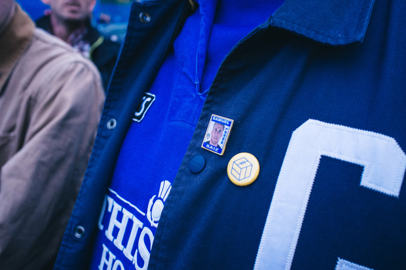 A close up of The Square Ball logo rendered on a badge, worn on a fan's jacket.